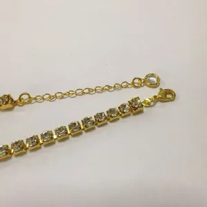 Close-up detail of gold-plated rhinestone tennis bracelet clasp and extension chain.