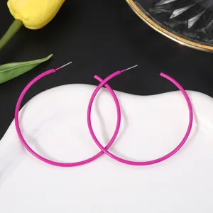 Overdreven roze metalen creoolse oorbellen, snoepkleurige gelakte afwerking, trendy sieradendetail.