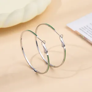 Gedetailleerde close-up van elegante zilveren oorbellen met chique groene emaillen druppeldetails.