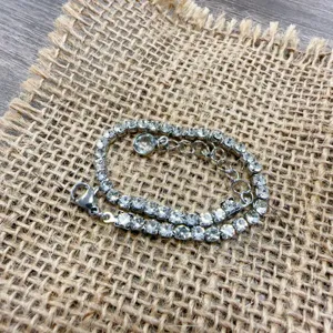 Closeup of sparkling rhinestone tennis bracelet with adjustable chain and lobster clasp.