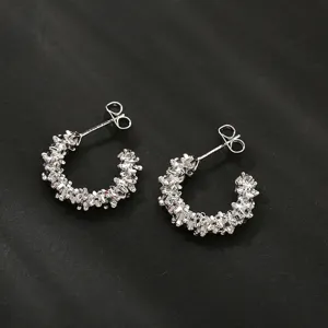 Gedetailleerd overzicht van onregelmatige zilveren oorringen, minimalistische sieraden.