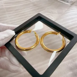 Detailopname van dikke gouden creolen oorbellen, gladde gepolijste messing afwerking.