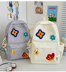 Japanse stijl studenten rugzak met bloem patches en schattige berenhanger in detail.