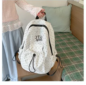 White canvas backpack with black polka dots, front drawstring pocket and zipper design.