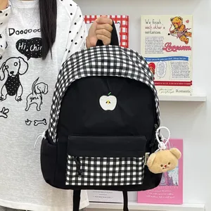 Détail de sac à dos vichy noir et blanc avec broderie de pomme et poche avant.