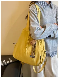 Gedetailleerde close-up van de stijlvolle gele nylon tas-rugzak met schattige berenhanger.