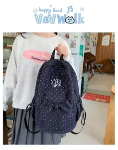 Detailed view of stylish navy blue polka dot backpack with front drawstring pocket.