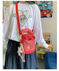 Gedetailleerd opname van een rood-witte geruite emmertas met schattige aardbei patch en hangers.