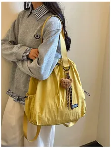 Gedetailleerd overzicht van gele nylon trekking rugzak en multifunctionele shopper tas.