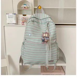 Gedetailleerd uitzicht op gestreepte canvas rugzak met schattige berenhanger aan plank.
