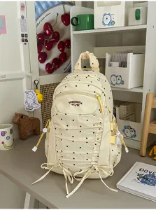 Gedetailleerd overzicht van een stijlvolle beige rugzak met stippen en handig voorvak.
