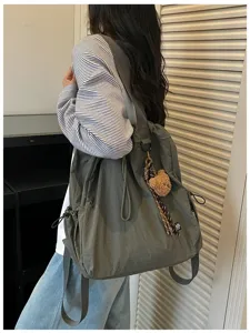 Gedetailleerd overzicht van grote donkergroene nylon rugzak shopper met berenhanger.