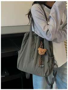 Gedetailleerd overzicht van de veelzijdige nylon drawstring rugzak tas met schattige berenhanger.