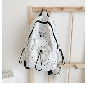 White polka dot backpack featuring black drawstrings and front pocket, casual minimalist design.