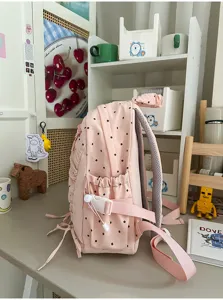 Gedetailleerd zijaanzicht van de roze rugzak met polkadots, zijvak en verstelbare gesp.