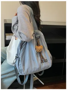 Lichtblauwe nylon rugzak en shopper tas met pluche berenhanger, gedetailleerd overzicht.