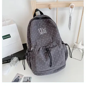 Grey polka dot backpack detail, casual student school bag with drawstring front pocket and letters.