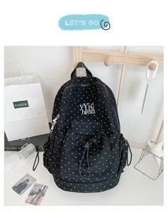 Detail view of black polka dot canvas backpack featuring front drawstring pocket and straps.