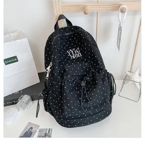 Black polka dot casual student backpack with large capacity and drawstring pocket design detail.