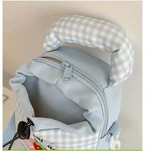 Gedetailleerd overzicht van de lichtblauwe ruitjes canvas rugzak met schattig aardbeiborduursel.