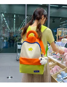 Detailed view of the cute color-block student backpack with plush charm and spacious interior.
