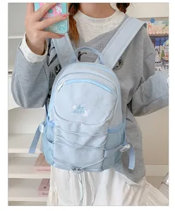 Light blue casual drawstring backpack closeup showcasing detailed embroidery and mesh side pockets.