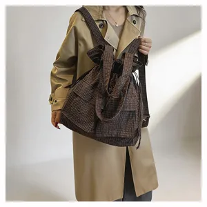 Detail view of the brown plaid utility drawstring backpack, oxford fabric convertible shoulder bag.