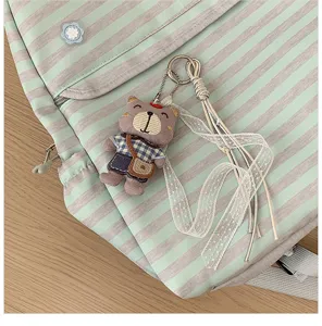 Close-up detail van een gestreepte rugzak met schattige teddybeer pluche hanger op hout