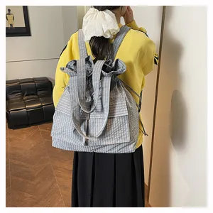 Detailed view of grey white plaid canvas drawstring backpack for casual school and travel use.