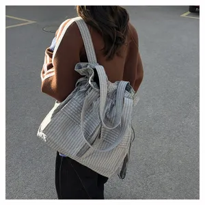 Detail view of a fashionable utility plaid drawstring backpack and shoulder bag for travel.