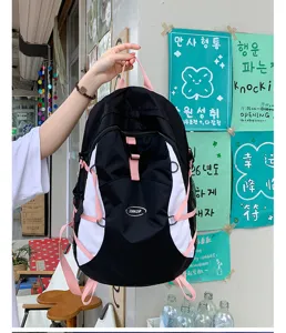 Detailed view of black and white backpack with pink straps and outdoor webbing design.