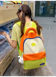 Detail shot of a colorful student backpack with star patch, plush pendant, and durable dual straps.