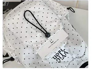 Fashionable black and white polka dot backpack detail showing drawstring closure and front pocket.