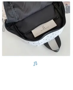 Detailed view of the interior compartment and zipper pocket of the minimalist polka dot backpack.