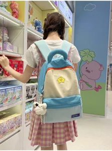 Cute color block student backpack with plush pendant, stylish large capacity school bag.