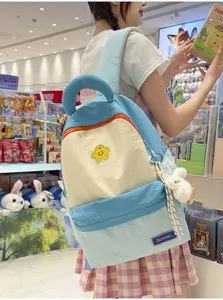 Cute color-blocking student backpack detail in store, featuring smiling star badge and plush.
