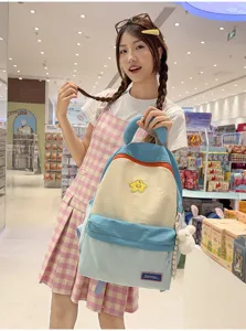 Close-up detail of cute color block student backpack with smiley star patch and plush pendant.