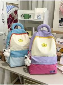 Cute colorblock student backpack with plush charm, spacious casual school bag for daily use.