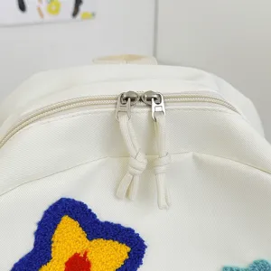 Witte canvas casual rugzak detailweergave met dubbele metalen ritsen en sterren.