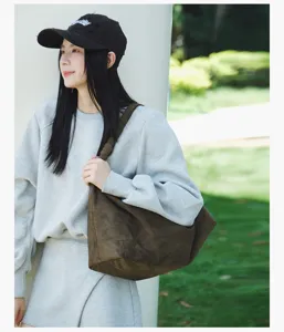 Detailed view of casual brown suede shoulder bag worn by model outdoors, minimalist hobo style.