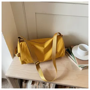 Gros plan sur le sac bandoulière cylindrique en nylon jaune avec une sangle réglable.
