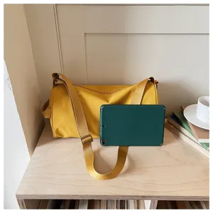 Sac bandoulière cylindrique minimaliste en nylon jaune, grande capacité et design décontracté.