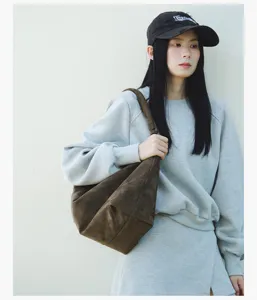 Detailed view of the brown suede underarm shoulder bag worn in a casual lifestyle outfit.
