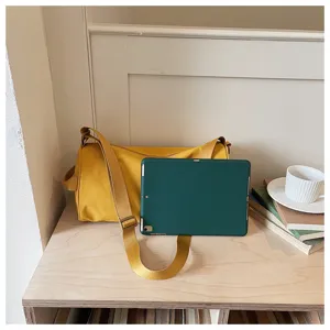 Vue détaillée du sac à bandoulière cylindrique jaune minimaliste sur un bureau en bois.