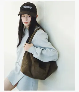 Detail shot of brown suede shoulder bag worn by model, casual style, large capacity design.