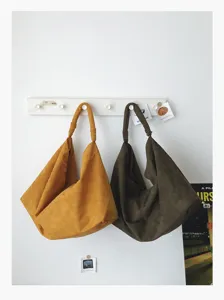 Detailed view of slouchy suede underarm shoulder bags in mustard and dark green tones.