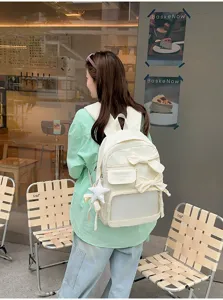 Vista detallada de la mochila beige con lazos elegantes y un bolsillo frontal transparente.