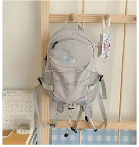 Details of the light grey casual canvas backpack featuring front drawstring and mesh pockets.