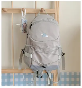 Detail view of a stylish casual backpack with drawstring and side mesh pockets in light grey.