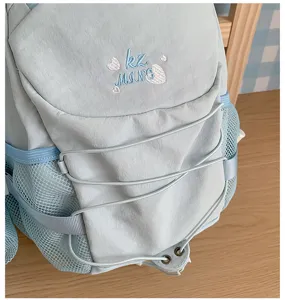 Light blue backpack detail showing front elastic drawstrings, mesh side pockets and cute embroidery.